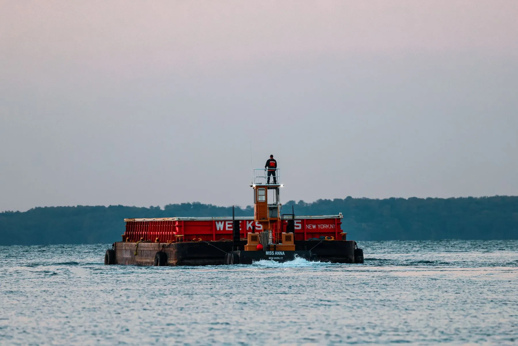 A tug pushing a construction barge along the coast