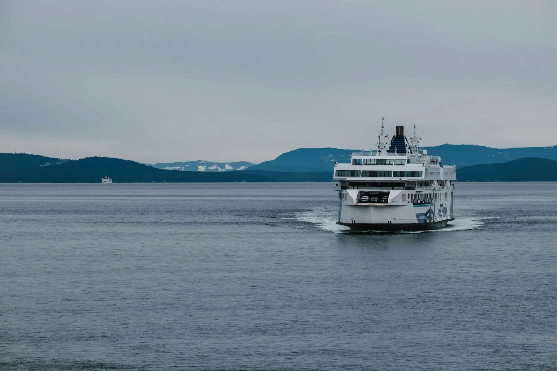 A ferry crossing a sound with mountains behind
