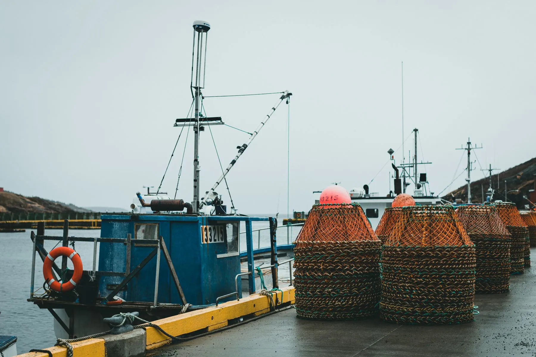 Crab pots stacked beside fishing boats on a wet dock