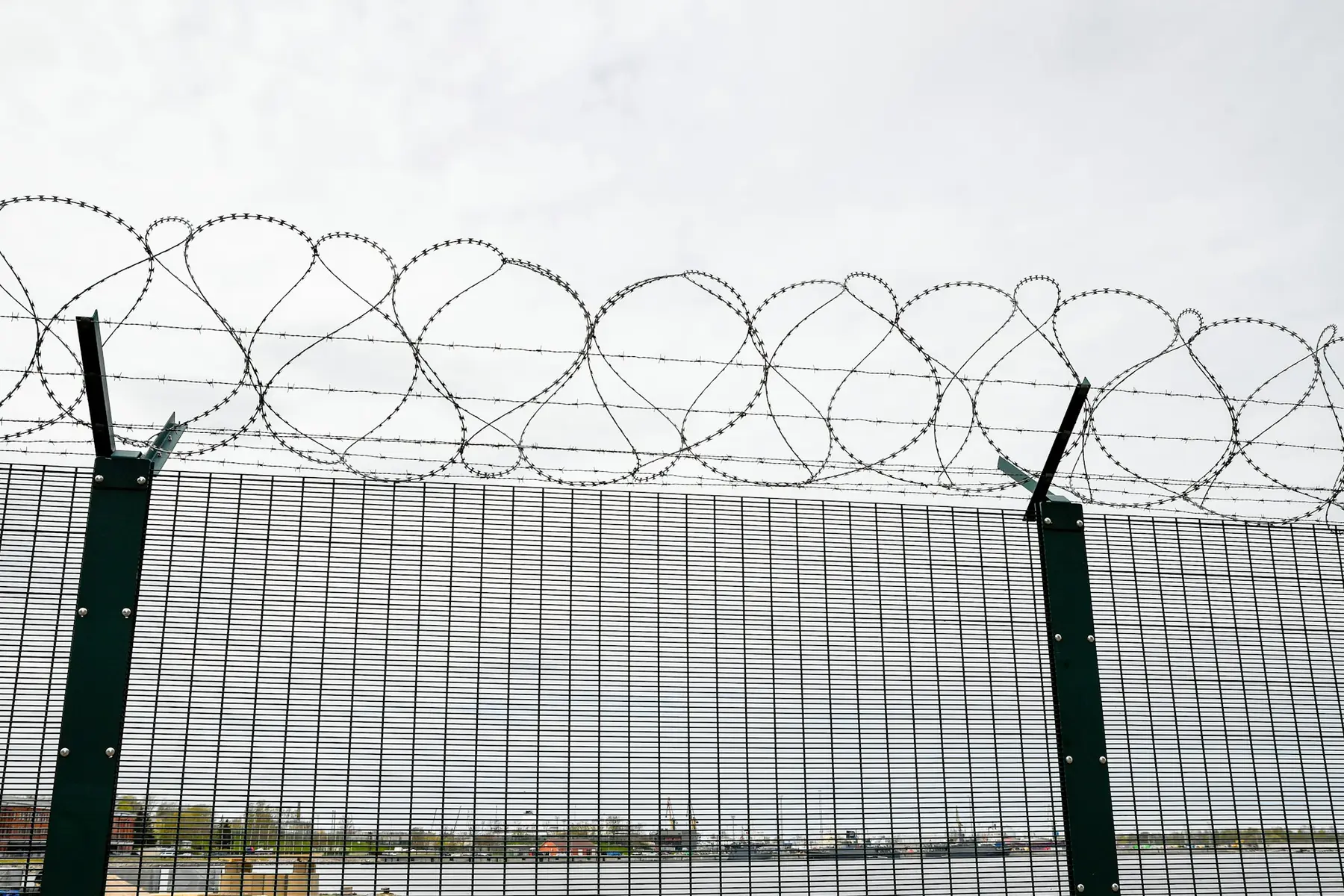 A secure perimeter fence topped with razor wire at the waterfront