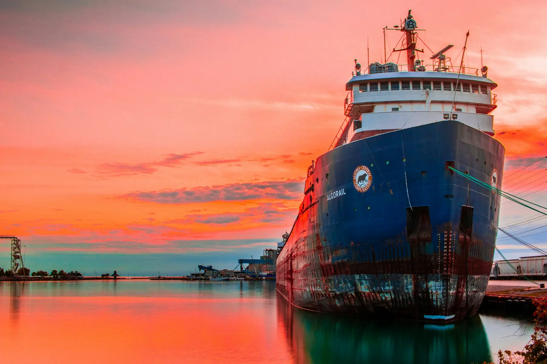 A cargo ship moored at sunset under a red sky