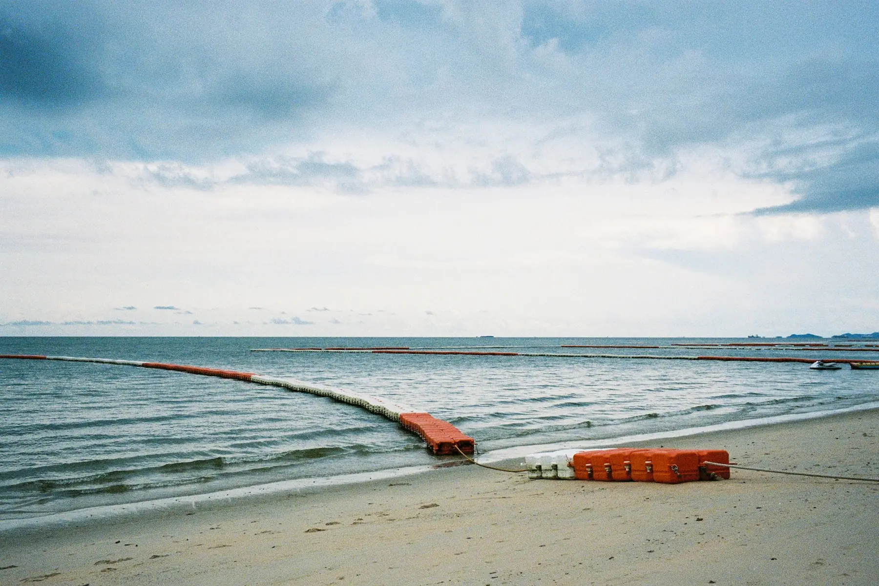 A containment boom staged along a beach at the waterline