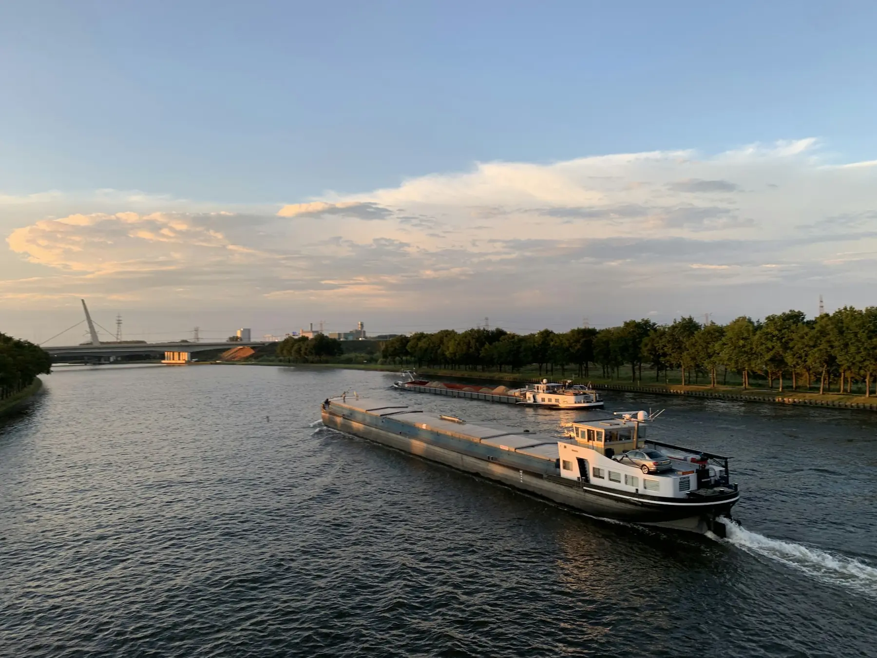 A towboat moving barges on a calm river at dusk