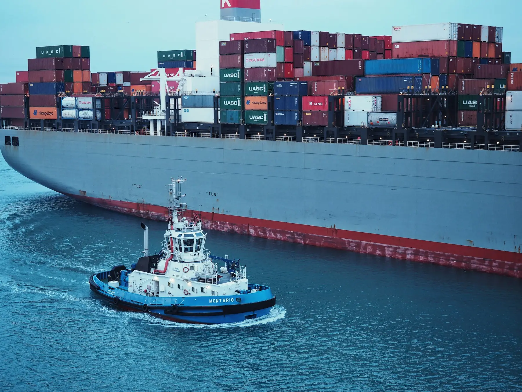 A tug assisting a fully loaded container ship