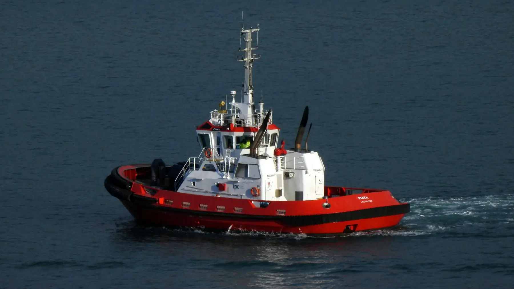 A red and white harbor tug on dark water